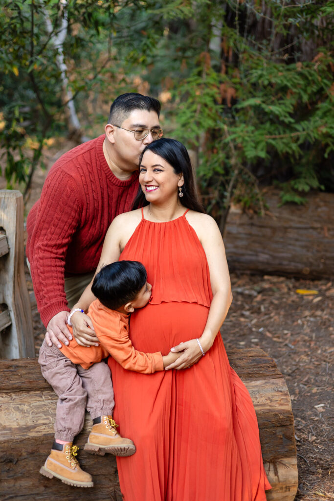 Family snuggling on wooden bench during Bay Area maternity photo session – Ellobelle Photography