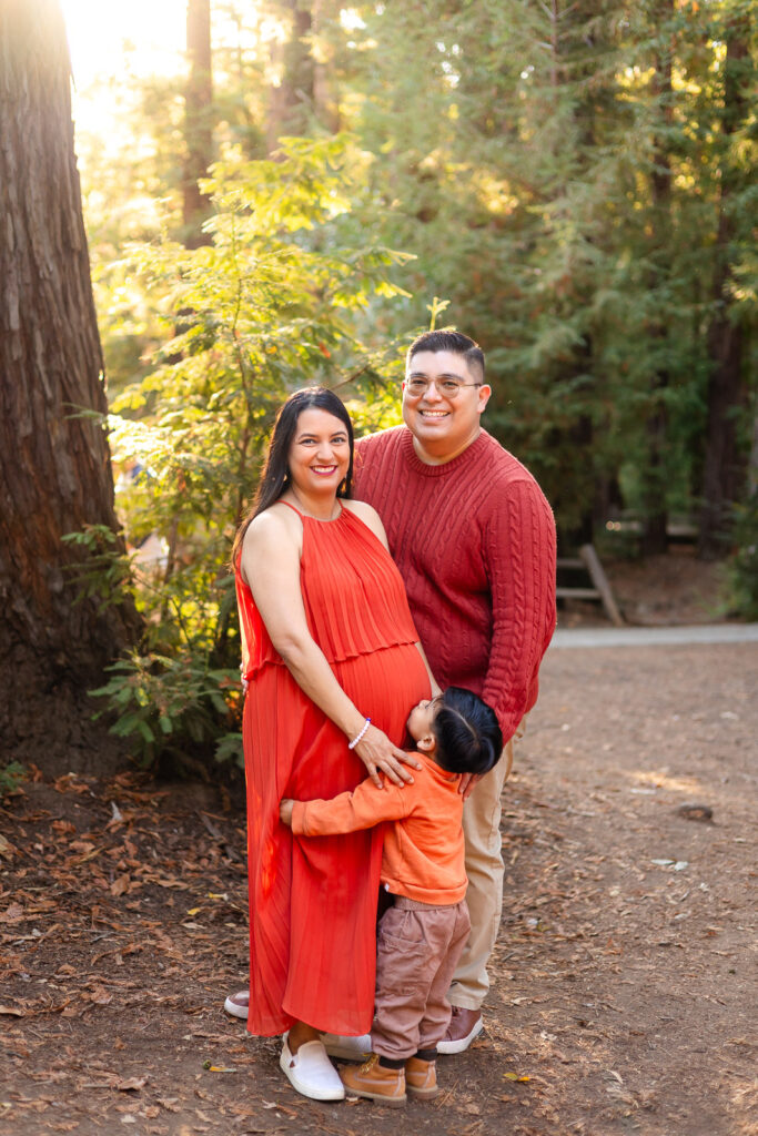 Family smiling with toddler hugging baby bump during golden hour maternity session – Ellobelle Photography