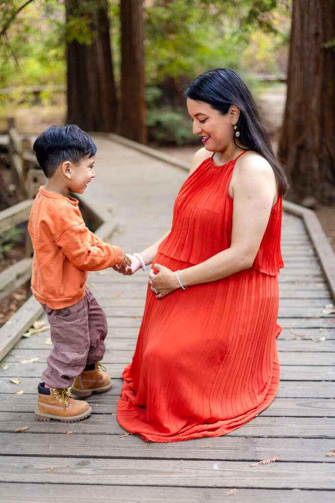Young boy holding hands with his pregnant mom during outdoor maternity shoot – Ellobelle Photography