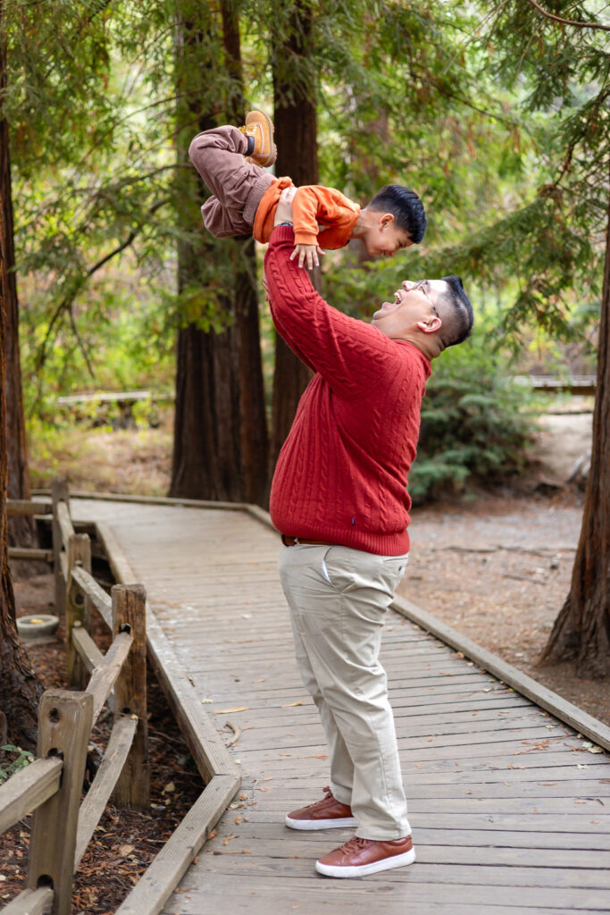 Dad lifting his son high during playful maternity photoshoot