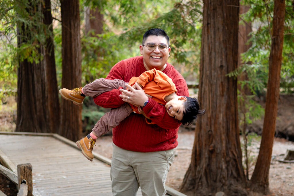 Dad holding laughing toddler in redwoods during Bay Area family session
