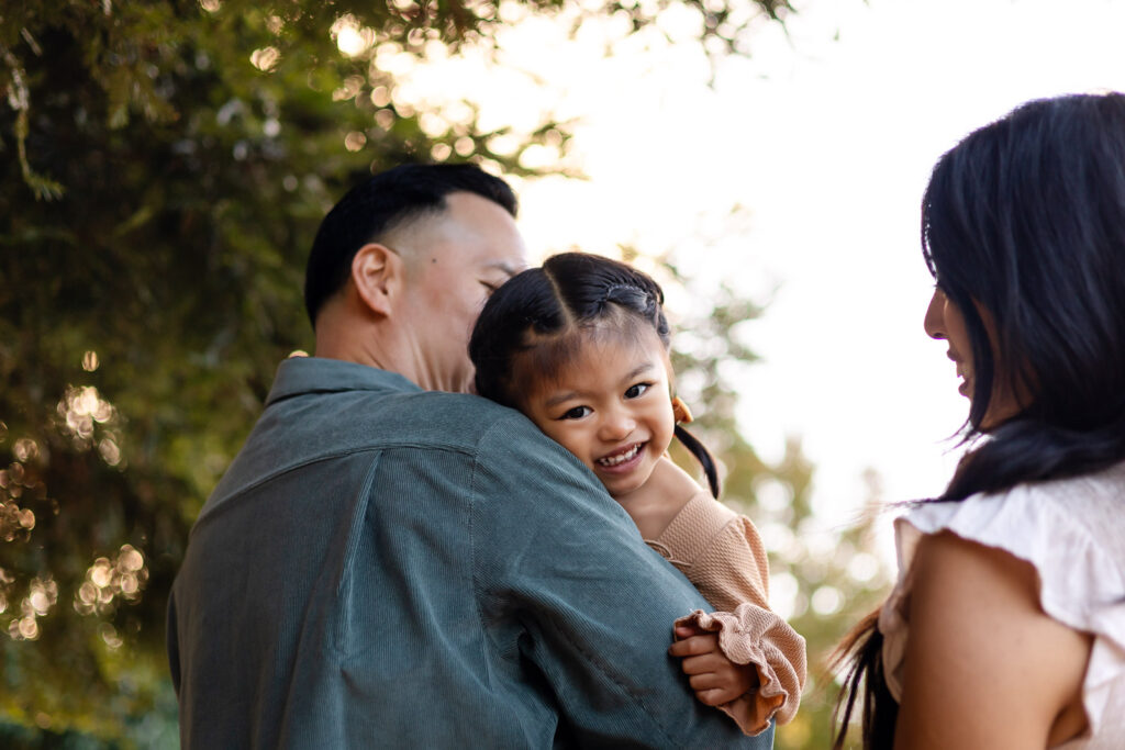 Daughter smiling while hugging dad during a joyful holiday photo session – Ellobelle Photography