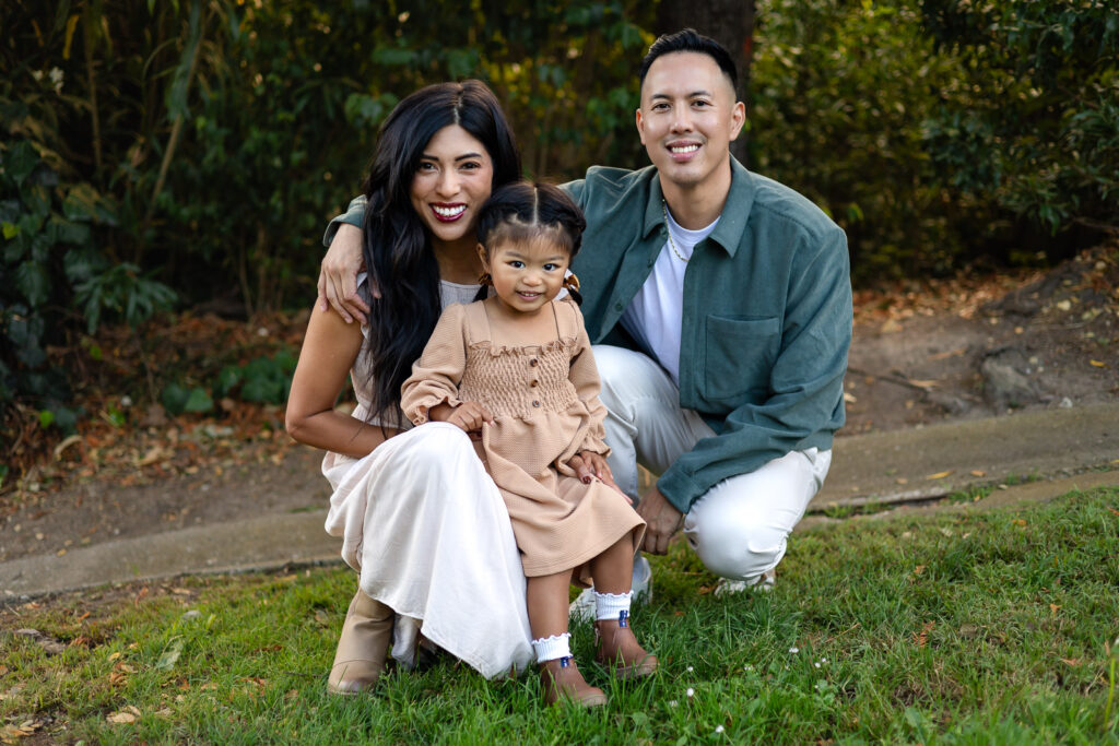 Young family smiling together in green park for holiday photo sessions – Ellobelle Photography