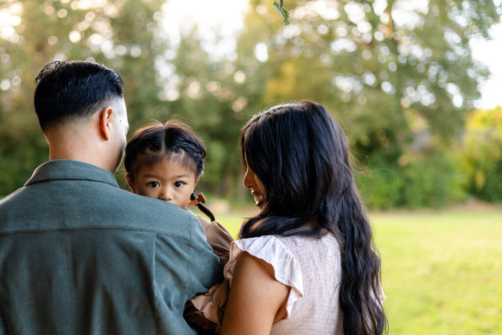 Parents holding daughter while walking through the park during a holiday photo session – Ellobelle Photography