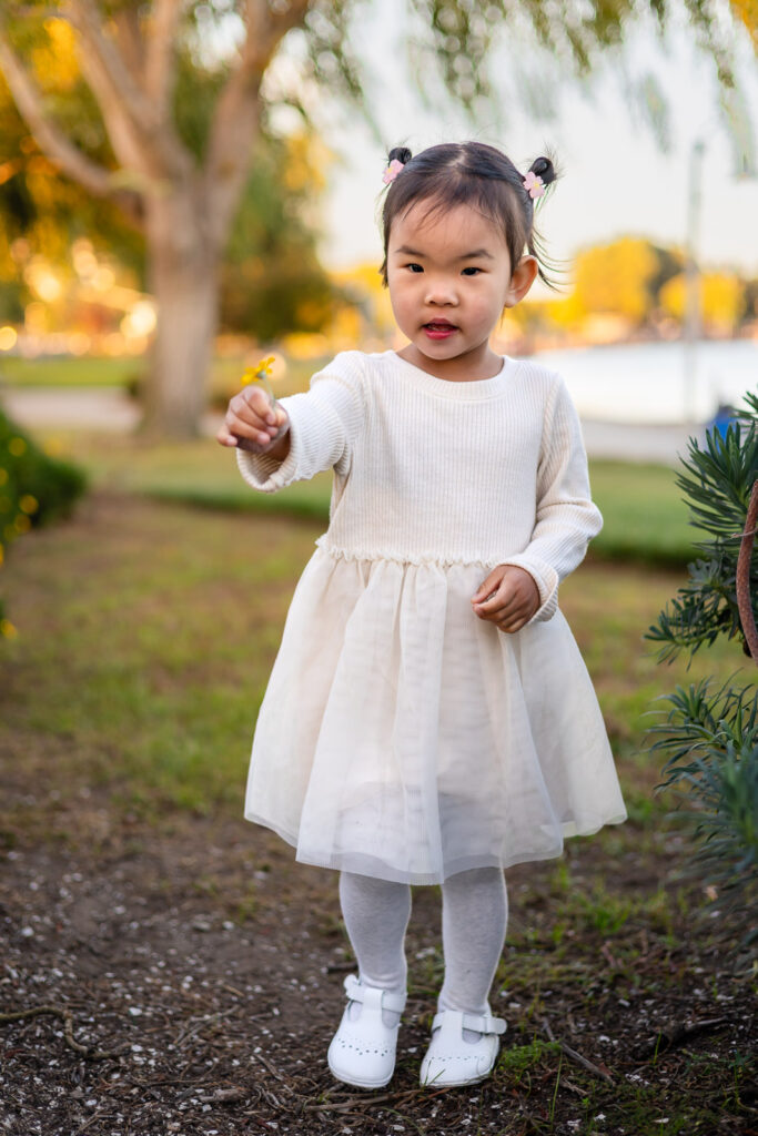 Little girl holding a flower near the lake at Leo Ryan Park