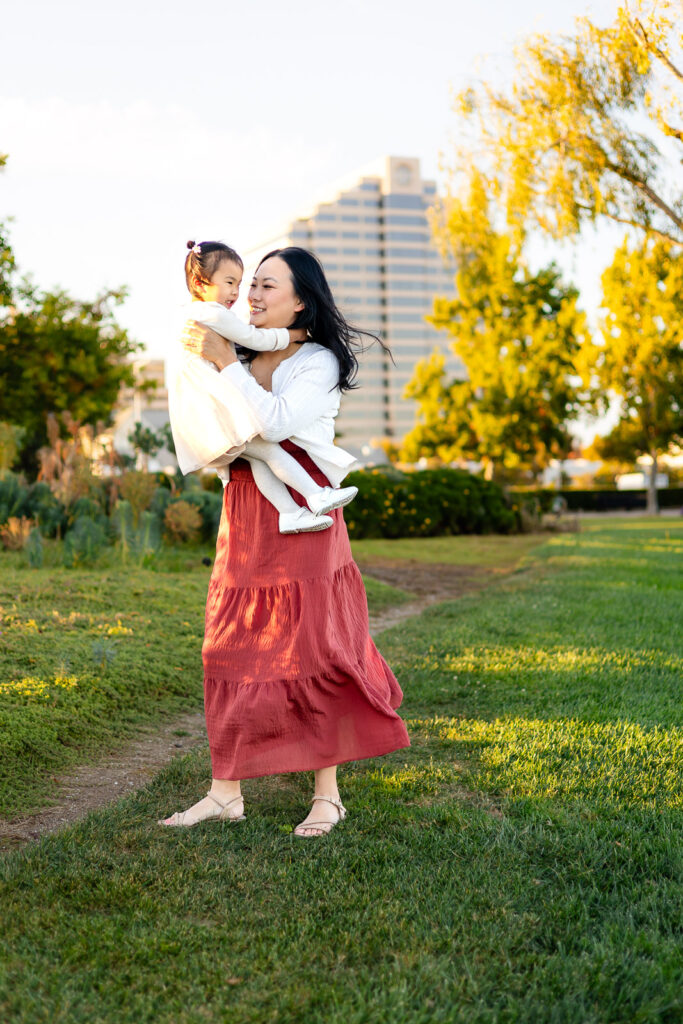 Mother twirling with daughter in a field at Bay Area shoreline park