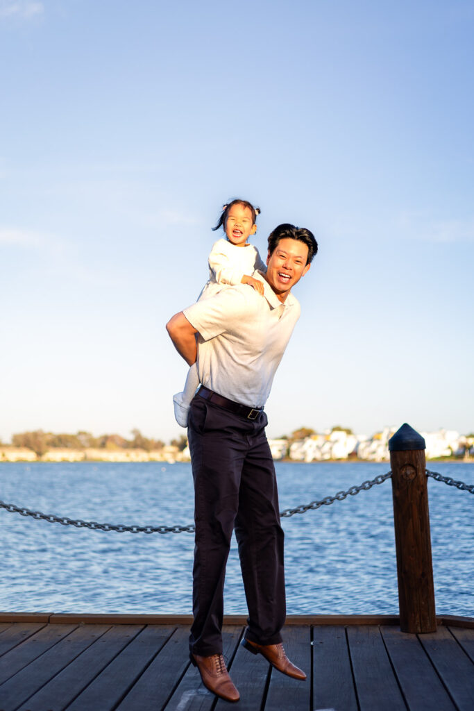 Dad lifting daughter for a piggyback ride on the dock at Foster City recreation area
