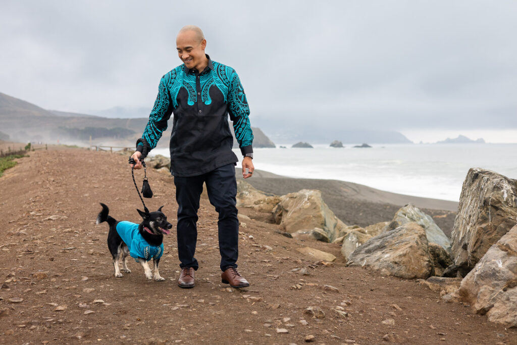 Man walking his happy dog along the beachside path during a photo session with dog