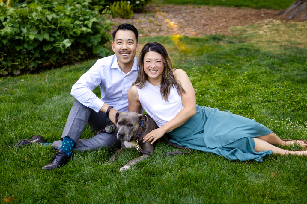 Couple sitting on the grass with their dog during joyful pet friendly photo session