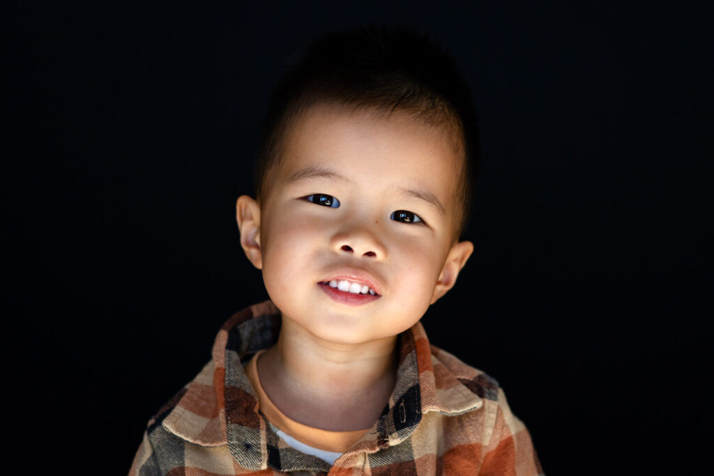 Smiling child during a modern studio portrait on a black backdrop by Bay Area Preschool Photographer at a Millbrae preschool studio setting – Ellobelle Photography