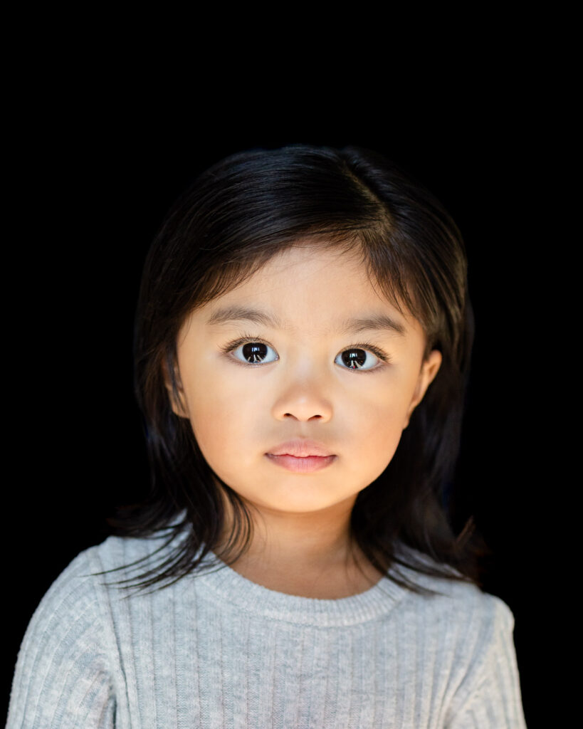 Child looking at the camera during a modern studio style portrait on a black backdrop by Bay Area Preschool Photographer in Millbrae – Ellobelle Photography