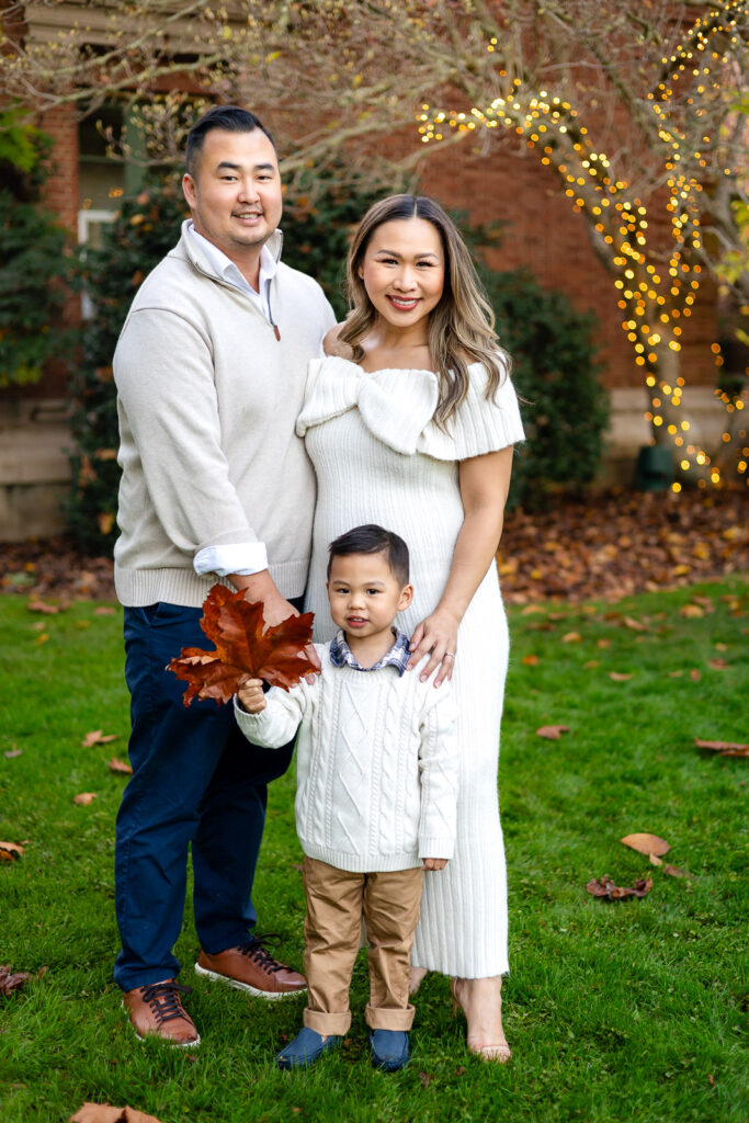 Family standing on the lawn at Filoli with holiday lights in the background during Christmas photos