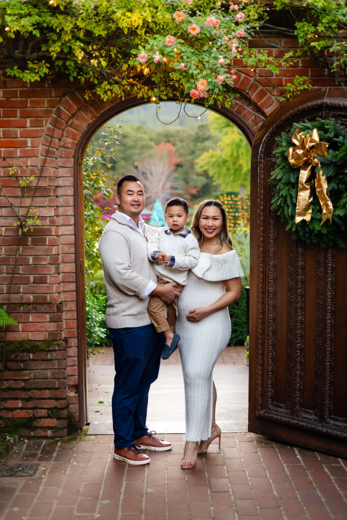 Family standing at the Filoli garden archway with holiday greenery during Filoli Christmas photography