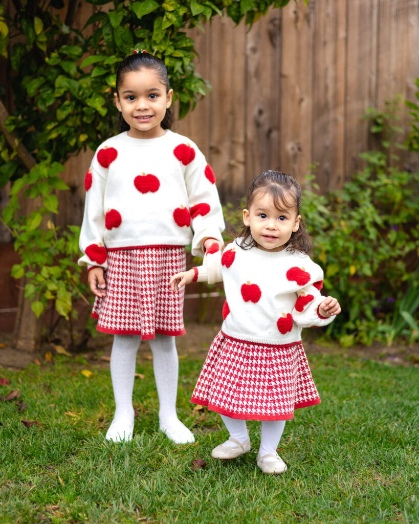 Sisters wearing matching outfits standing in the garden area at Millbrae Nursery School Ellobelle Photography