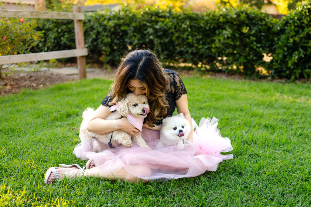 Woman hugging her two small dogs on the grass at a neighborhood park of SF dog photos
