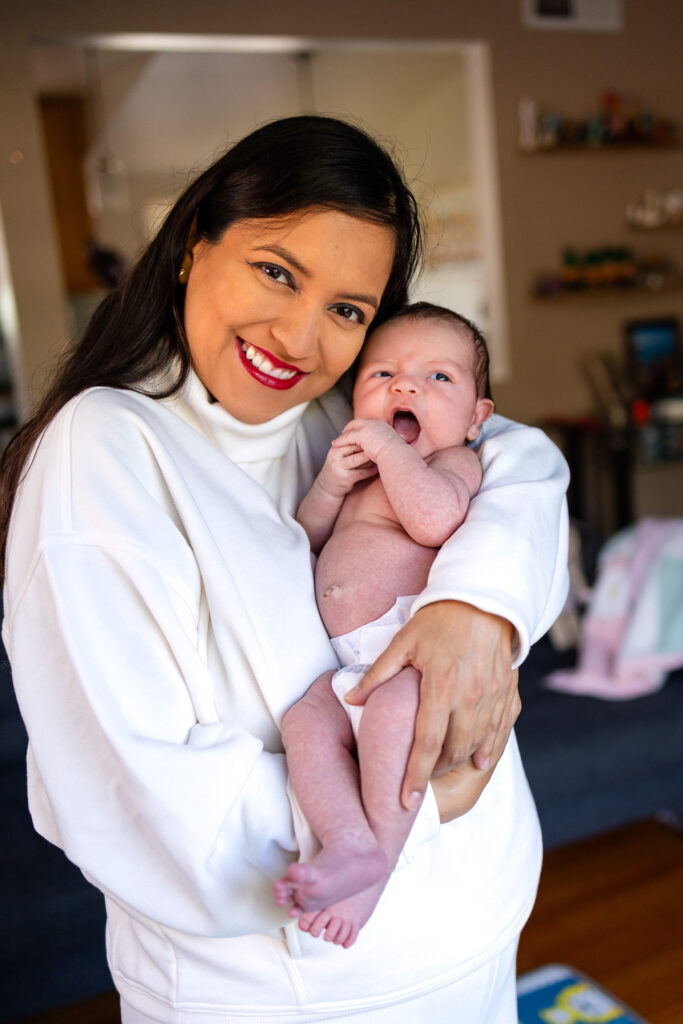 Mom holding her newborn during a cozy San Mateo lifestyle session with San Francisco Peninsula prenatal and postpartum services