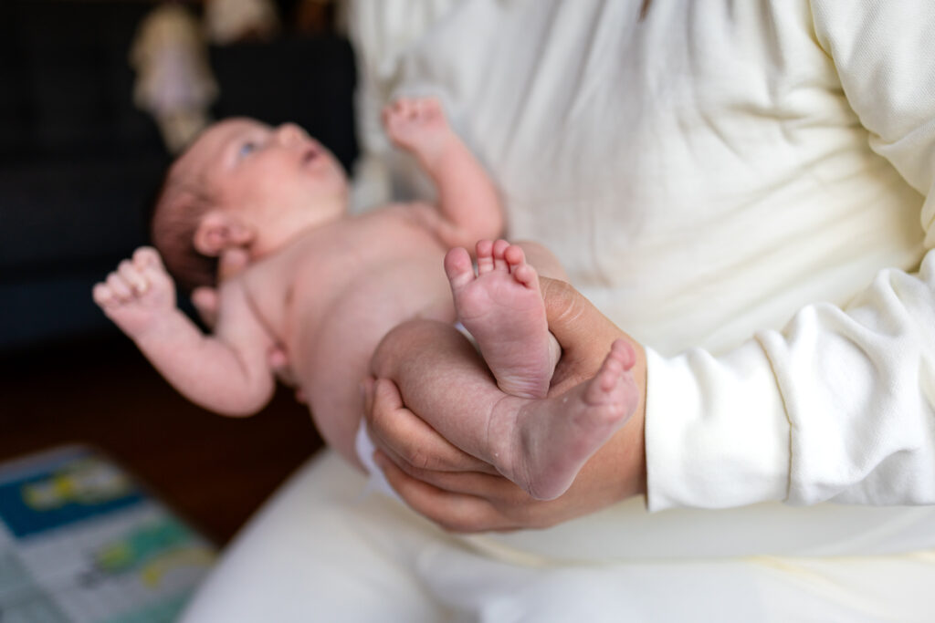 Parent cradling newborn during an in home San Mateo session connected to Bay Area prenatal and postpartum support