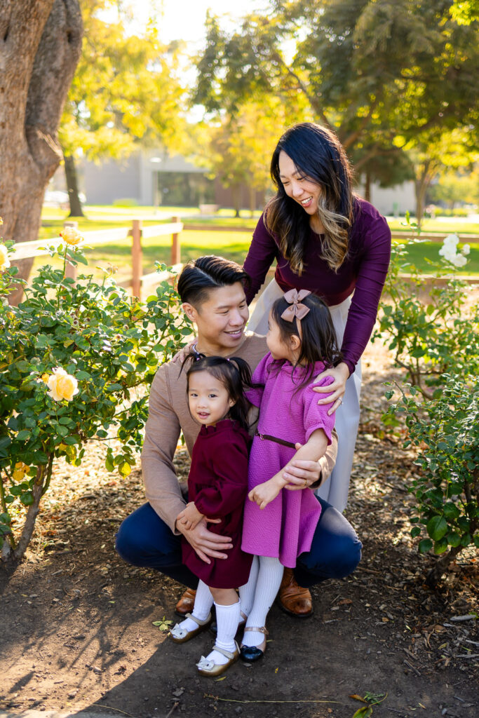 Parents and daughters sharing a playful moment in a park garden