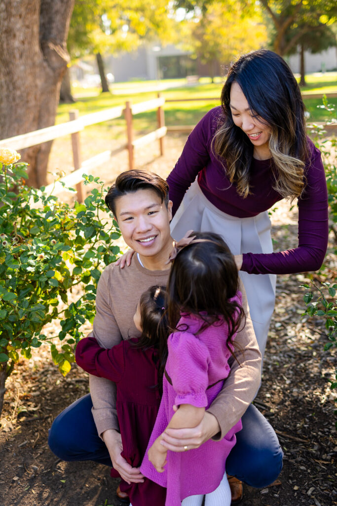 Family gathered close in a farm style park setting with rose bushes for helpful advice for stress free family photos