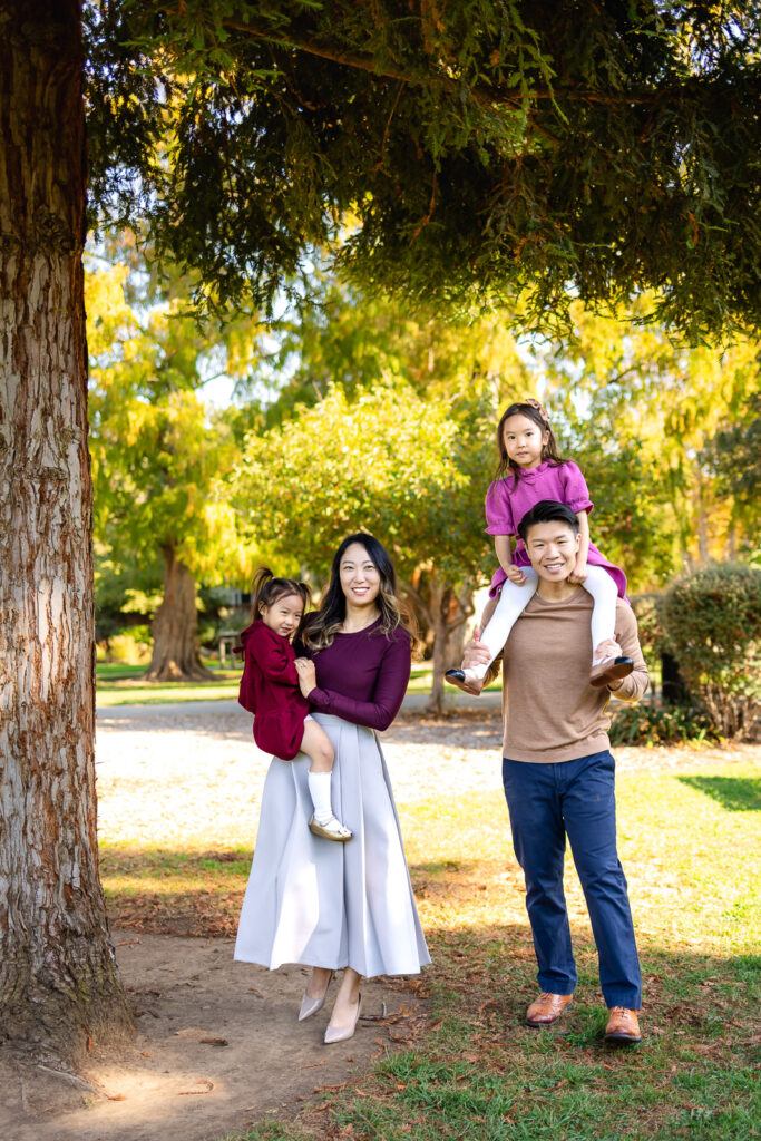Family posing under tall trees in a park for easy ways to help your session go smoothly