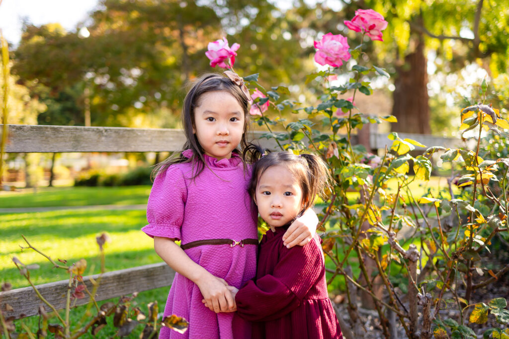 Sisters standing together near rose bushes in a park for simple tips for family photos