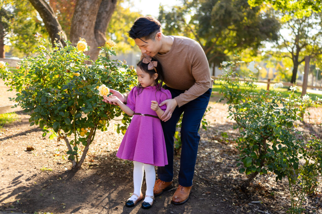 Dad helping his daughter explore flowers during Family Photoshoot Tips in a garden setting