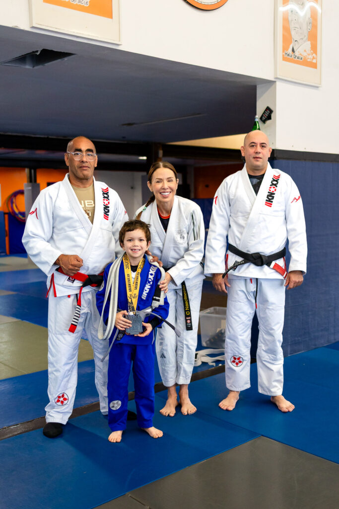 Kid with medal and belt promotion with instructors at during a Bay Area San Mateo promotion ceremony