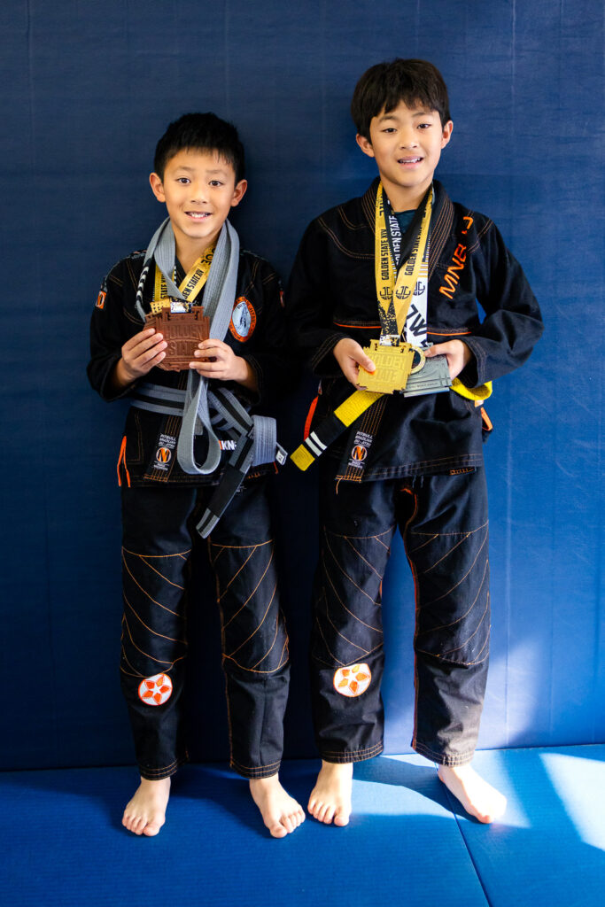 Two young brother athletes showing medals at kids martial arts