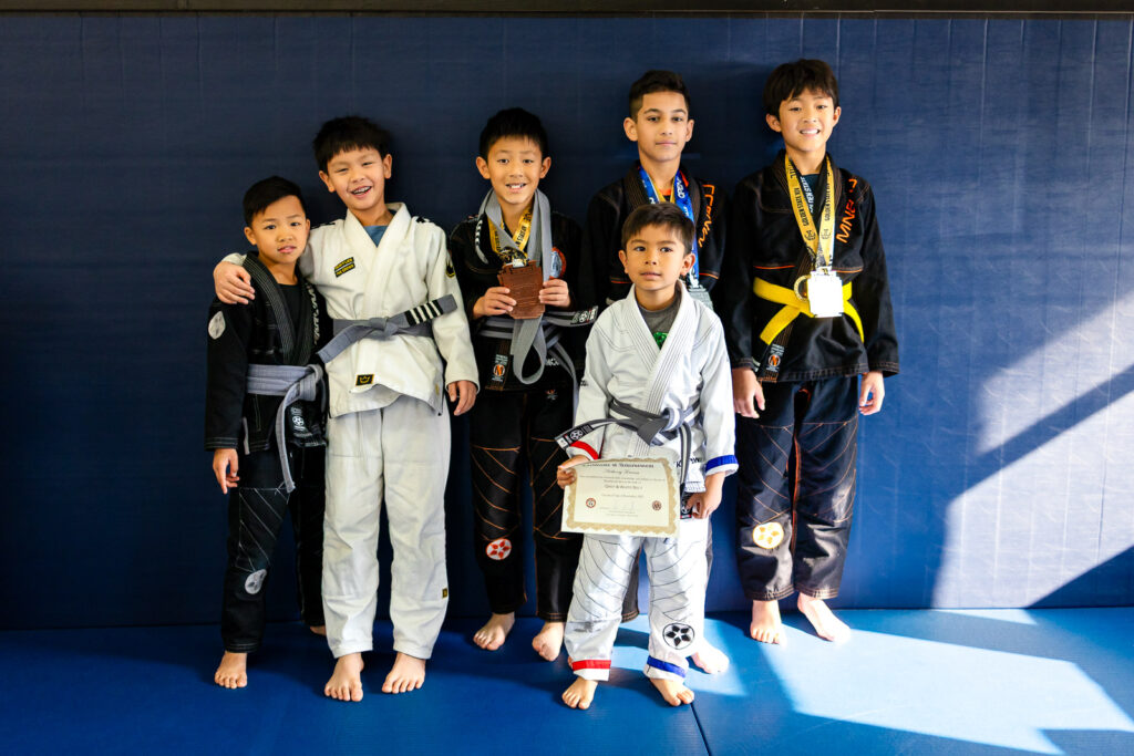 Group of young Nascimento Jiu Jitsu students posing with belts and certificates