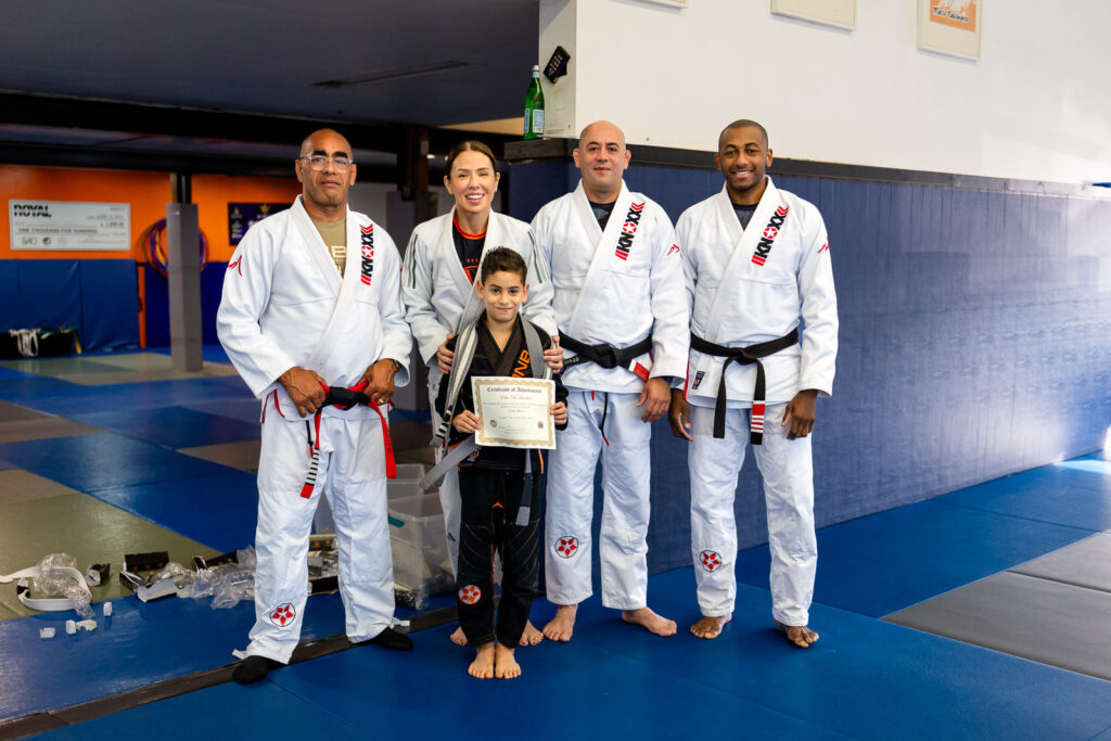 student receiving a promotion certificate with instructors in San Mateo