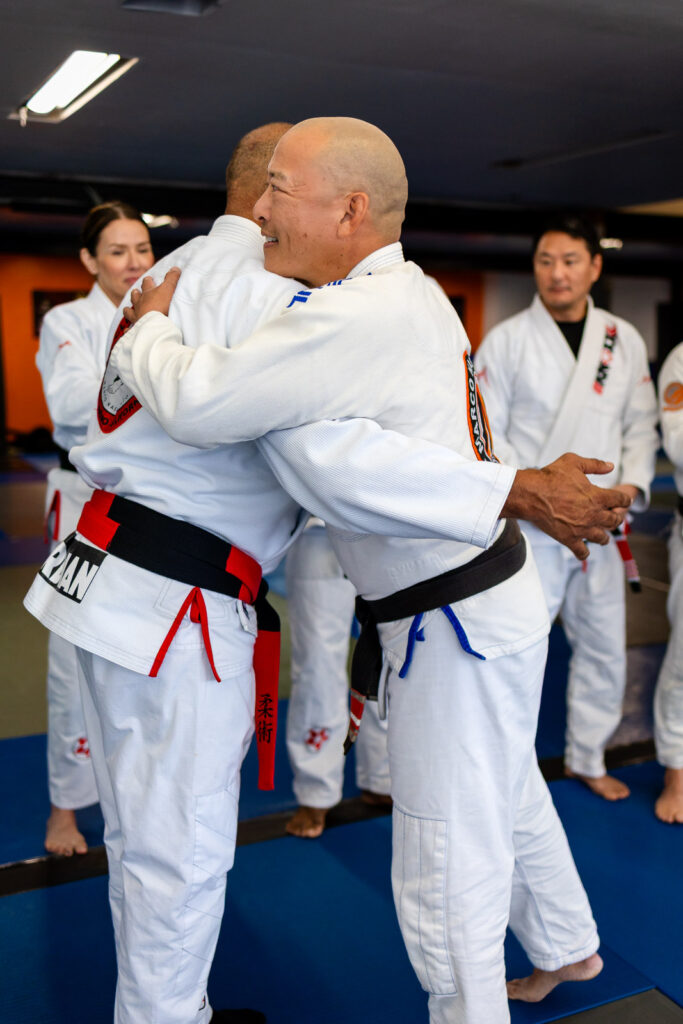 Warm embrace between two black belts during a candid moment during jiu jitsu class