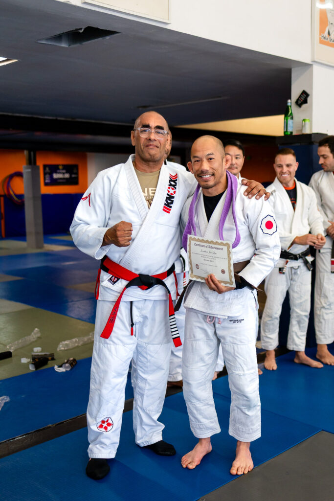 Marco Nascimento BJJ instructor posing with newly promoted brown belt student