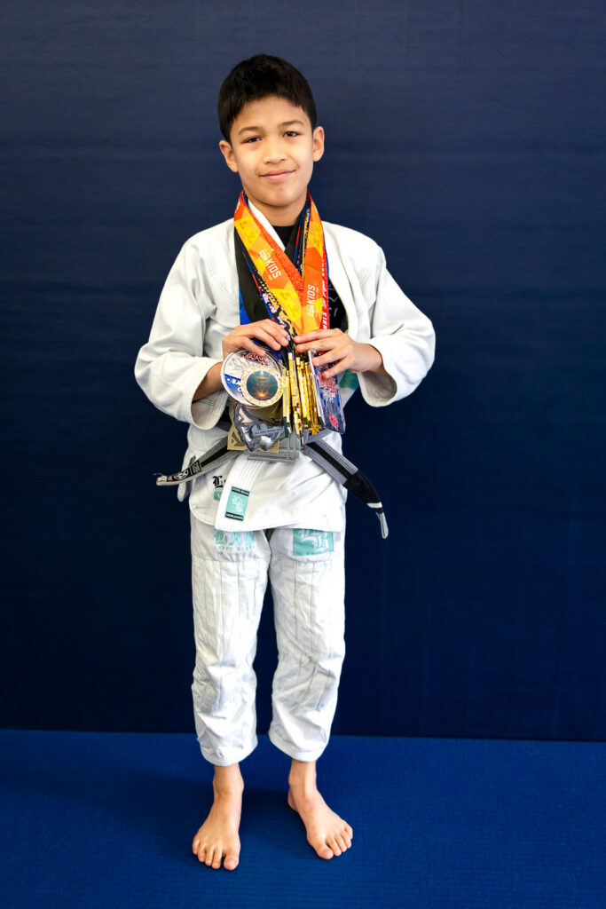 Jiu Jitsu student holding competition medals at a Bay Area San Mateo academy