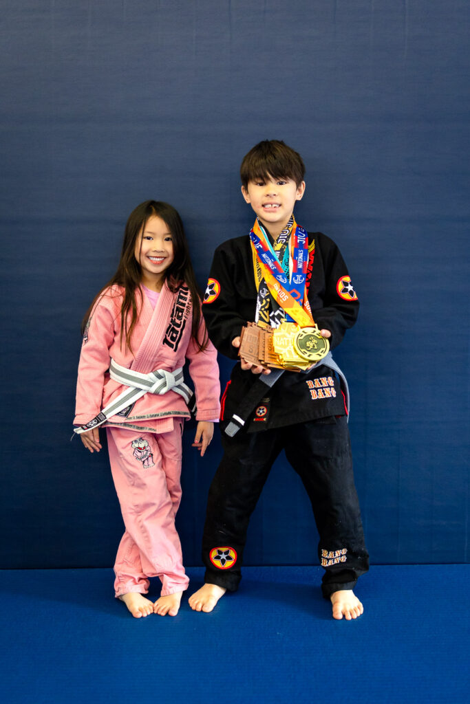 Two young athletes smiling and showing medals