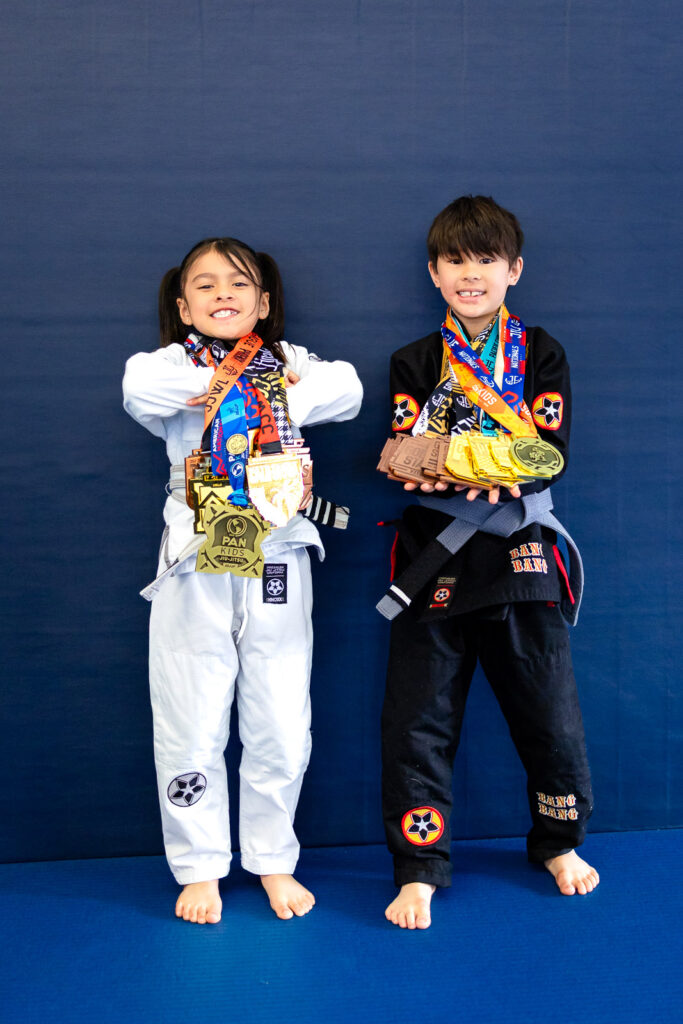Two Jiu Jitsu students posing together with competition medals