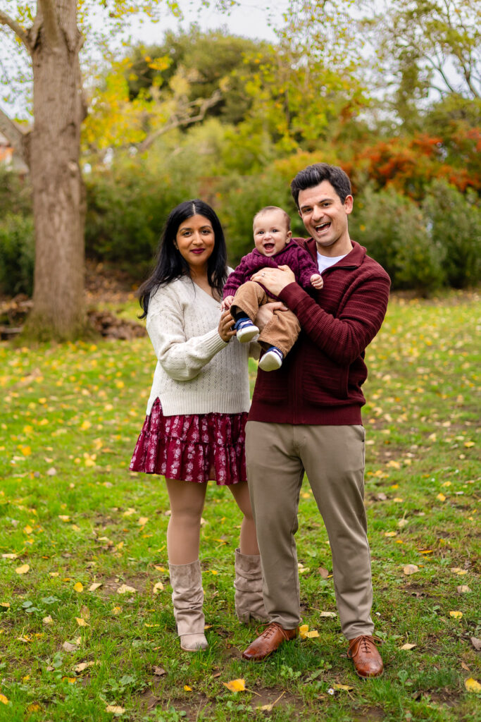Baby laughing while being held by his parents at Bay Area family photos in a quiet Millbrae park