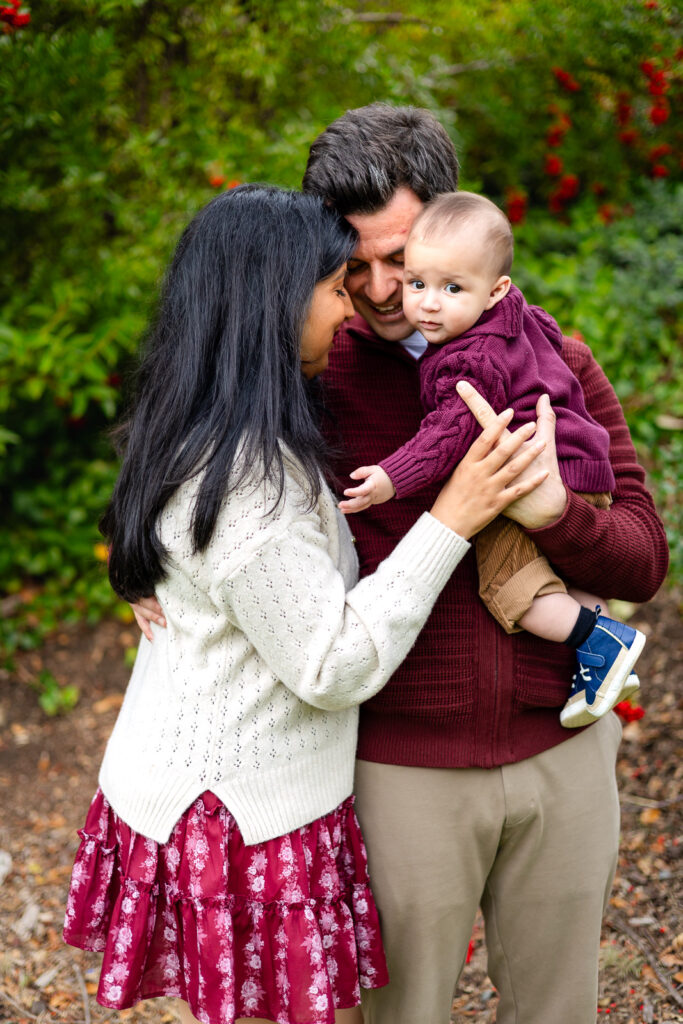 Family snuggling together with greenery and red berries at Meadows Park Millbrae Bay Area