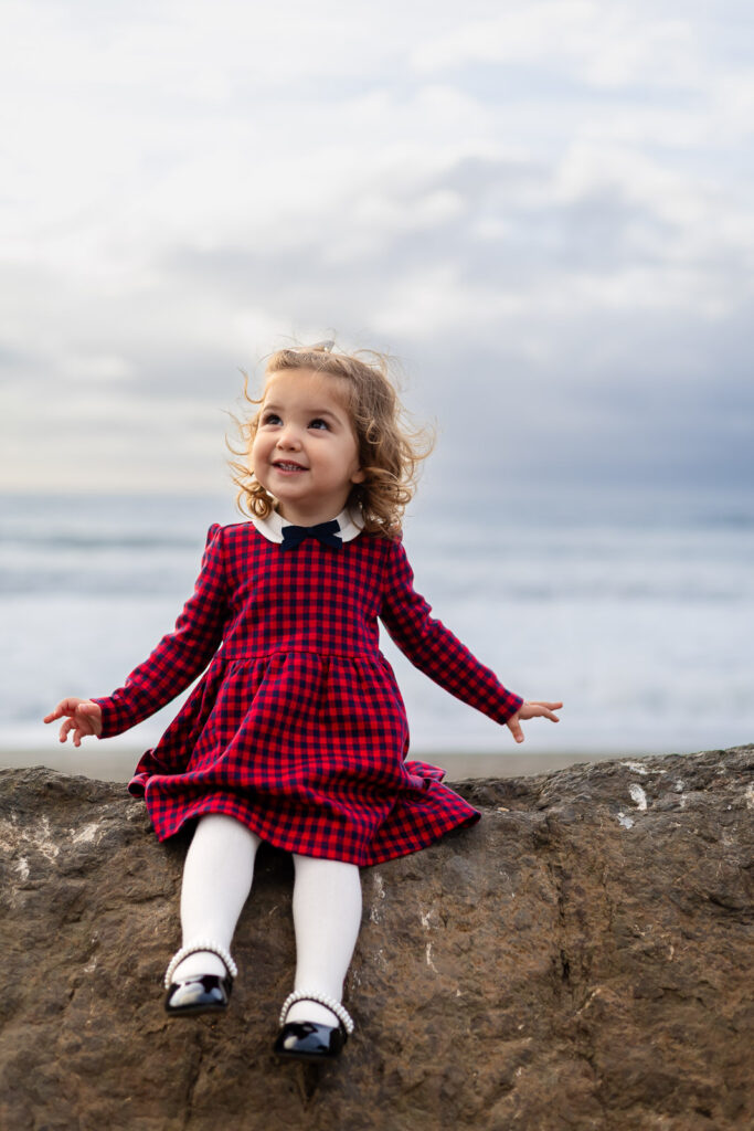 Toddler sitting on a rock at the coastline during a San Mateo parenting club session