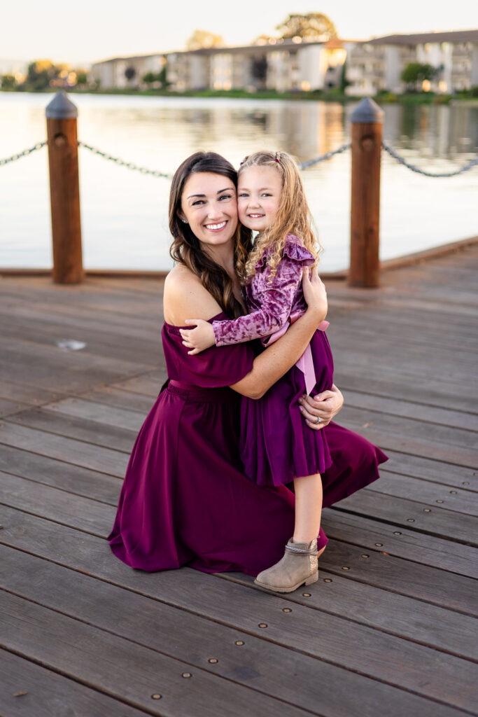 Mom hugging her daughter near the water at Leo Ryan Park for session day essentials guide