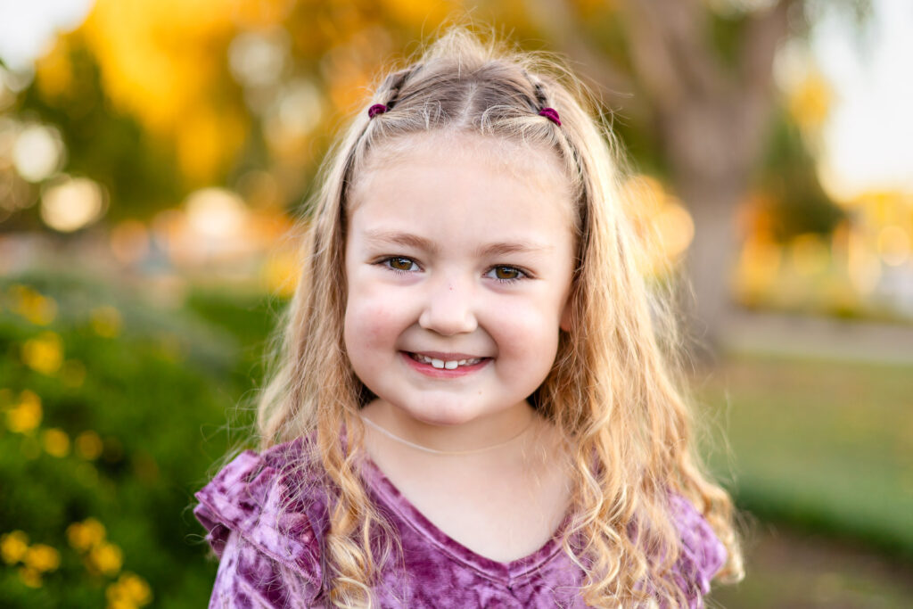 Young girl smiling in the gardens at Leo Ryan Park in Foster City for a what to have on hand for your session