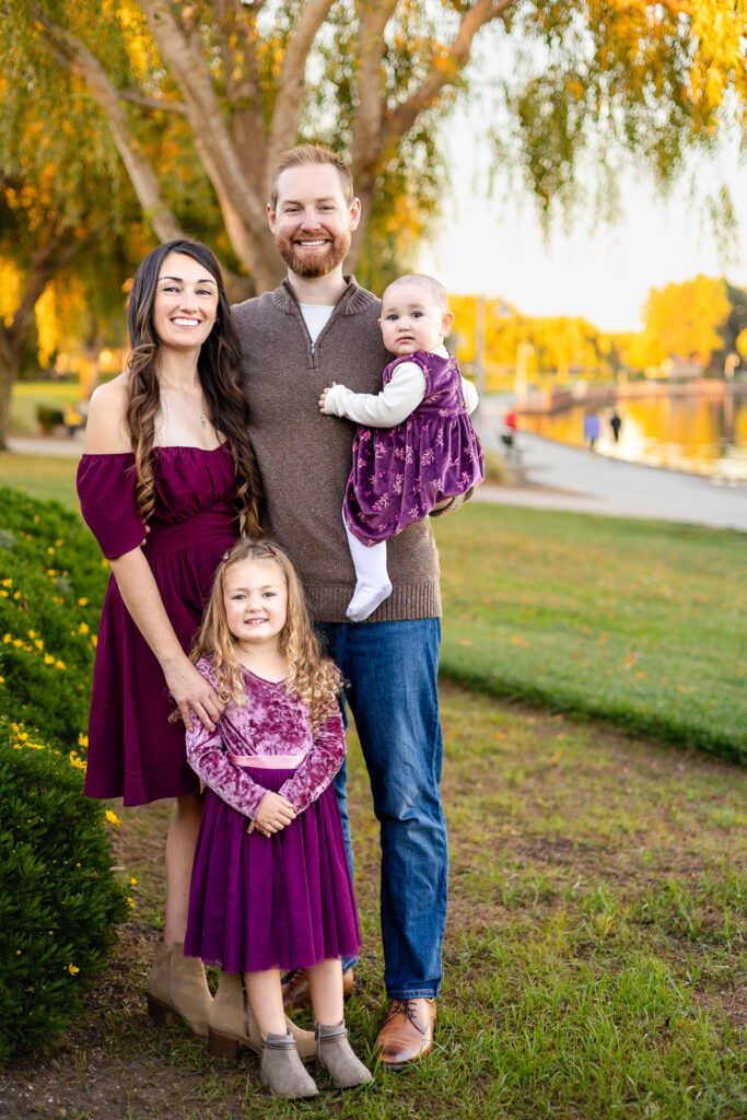 Family smiling together near the trees at Foster City Lagoon for a what to bring to your photo session articl