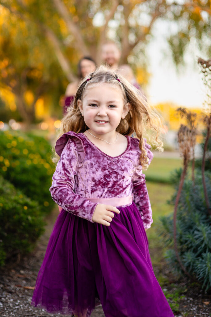 Little girl running along the garden path at Leo Ryan Park for a what to bring to a photoshoot blog