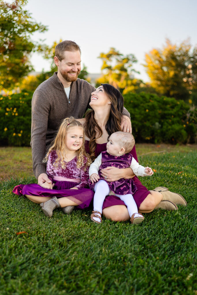 Family sitting together on the grass at a Foster City park for a what parents love having on hand for photos overview