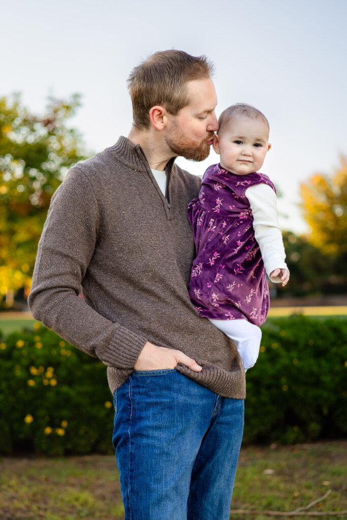 Dad kissing his baby’s head at a Millbrae park for a what to bring to a photoshoot checklist