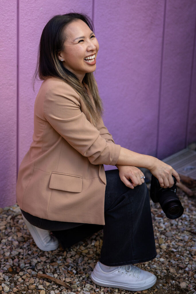A candid side profile of a photographer laughing while seated and holding a camera, reflecting natural candid photography for Bay Area parents.