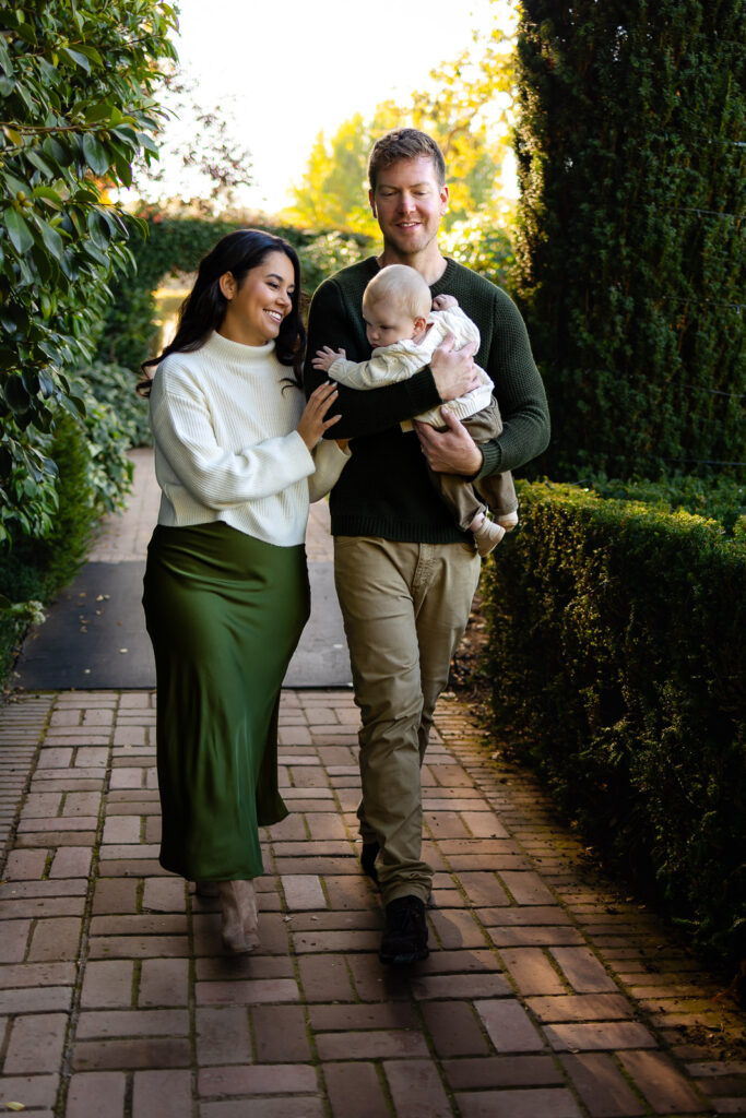 Parents walk side by side holding their baby, captured in natural light during a San Francisco lifestyle photographer session.