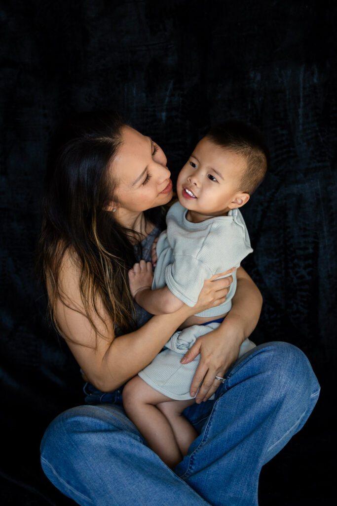 A mother smiles lovingly at her toddler as she cradles him close, creating a peaceful affectionate moment during Heartfelt Mama Minis