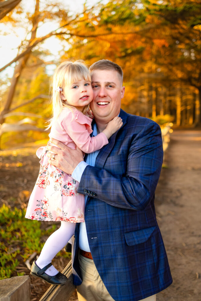 A father holds his daughter close as they smile toward the camera, photographed by a Bay Area photographer serving Half Moon Bay.