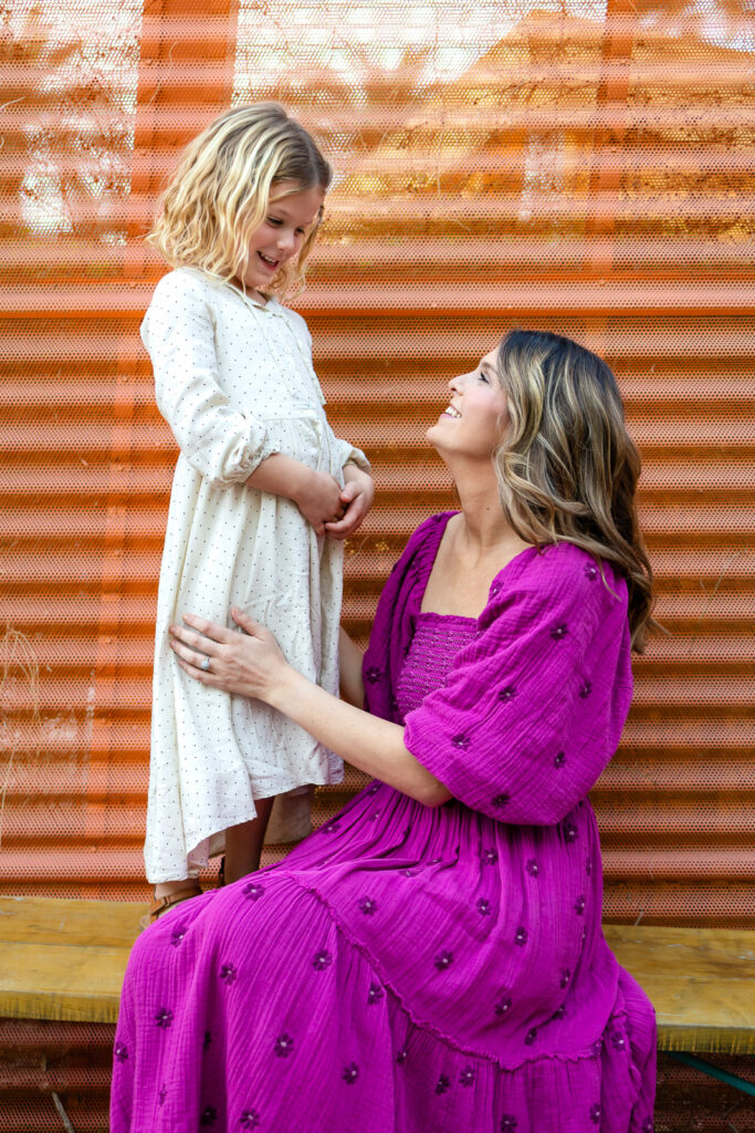 Mother kneeling and smiling up at daughter during joyful Palo Alto motherhood photos outdoor portrait