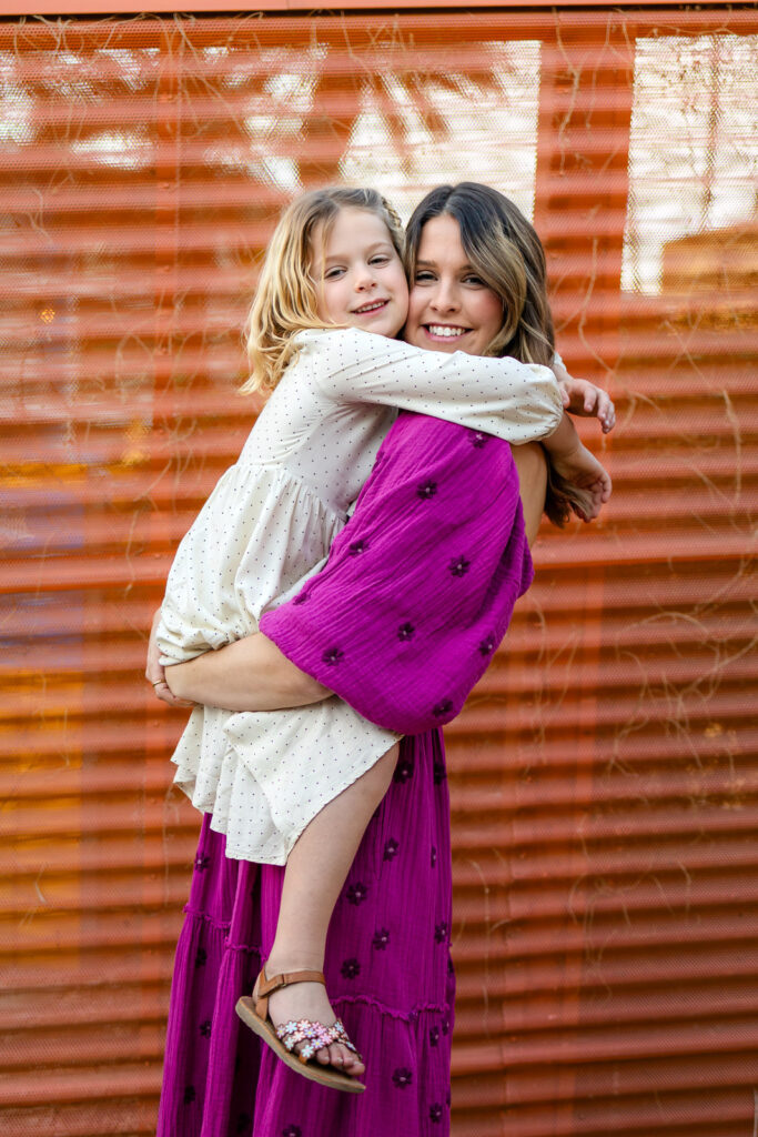 Mother smiling while holding her daughter during Motherhood mini sessions Peninsula candid connection moment